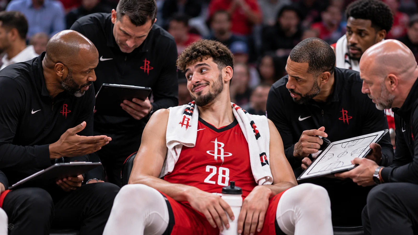 Alperen Şengün in current Houston Rockets No. 28 gear sitting on the bench while coaches crowd around him during a game timeout.