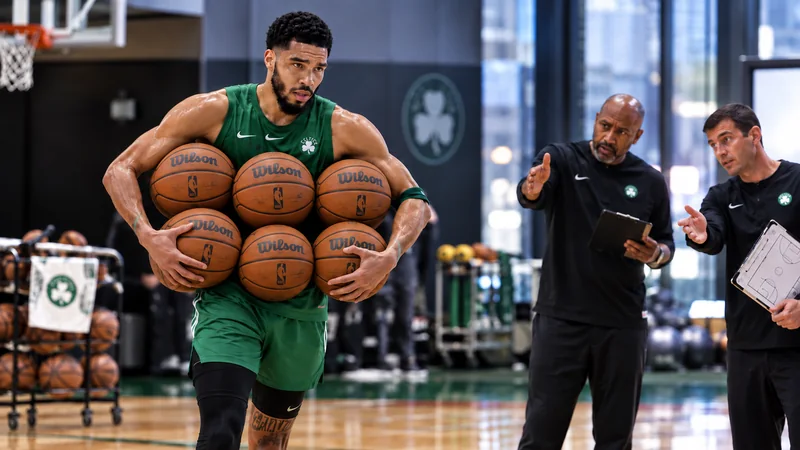 Satirical editorial image of Jayson Tatum carrying exactly six basketballs during a Boston practice while coaches look on.
