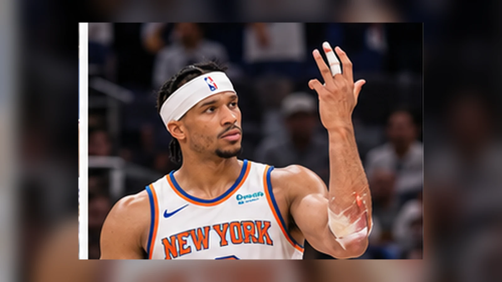 Josh Hart in current Knicks colors examines his damaged finger beside a medical X-ray during a satirical media session.